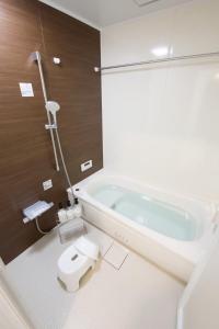 a bathroom with a bath tub and a toilet at Dual Residence Nakijin A in Koechi
