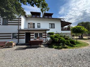 a white house with two benches in front of it at Dom Nad Brzegiem Wisły in Mozolice Małe