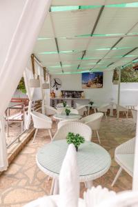 a dining room with white tables and white chairs at Ksamil Guesthouse Villa in Ksamil