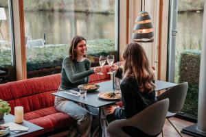 two women sitting at a table with wine glasses at Hotel Mitland in Utrecht
