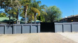 a gate in front of a fence with trees at Nvivi boutique hotel in Polokwane