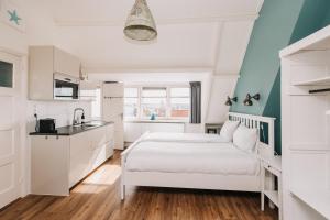 a white bedroom with a bed and a sink at Divi Divi Zandvoort in Zandvoort