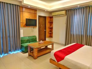 a bedroom with a bed and a table and a couch at Hotel Afford Inn in Dhaka