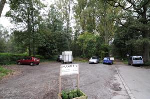 ein Schild vor einem Parkplatz mit geparkten Autos in der Unterkunft Waldhotel Unterbach in Düsseldorf