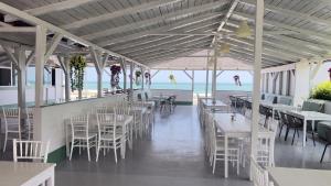 a restaurant with white tables and chairs and the beach at Vilele Delfin in Costinesti