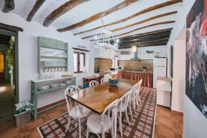 a kitchen with a wooden table and white chairs at Casa Mathilda in Fornes