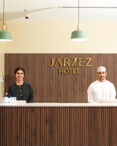 a man and a woman standing behind a counter at Jarzez Hotel Apartments Al Hail in Seeb