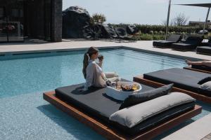 a couple sitting next to a swimming pool at SantAnna Luxury Suites in Imerovigli