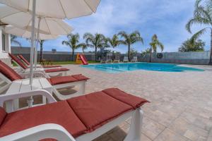 a pool with chairs and an umbrella and a slide at Jungle Holiday Villa in Avola
