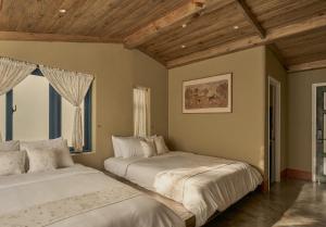 two beds in a bedroom with wooden ceilings at TONG Boutique Hotel in Phan Thiet