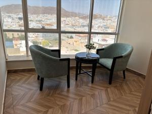 Ein Zimmer mit zwei Stühlen und einem Tisch vor einem Fenster in der Unterkunft راجان للشقق المخدومة in Ta'if