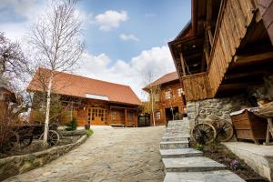 a building with a stone walkway next to a building at Székelyföld,Siklódi Kő Vendégház, Csűr in Şiclod