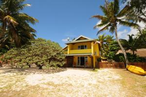 una casa amarilla con una tabla de surf amarilla delante de ella en Villa Eastern Wind, en Pointe d'Esny