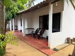 a porch of a house with chairs on it at Uluwatu Surf Hostel - Arugambay in Arugam Bay