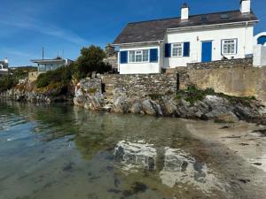 a house on the shore of a body of water at Boatman's Cottage in Rhoscolyn +8 photos
