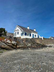 a white house on a rocky shoreline at Boatman's Cottage in Rhoscolyn