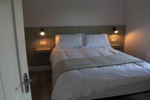 a bedroom with a large bed with white sheets and pillows at Sundaywell Cottage in Killyleagh