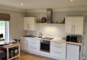 a kitchen with white cabinets and a table and a tableablish at Sundaywell Cottage in Killyleagh