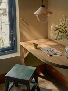 a wooden table in a corner with a stool and a lamp at TONG Boutique Hotel in Phan Thiet