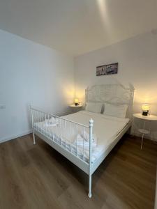 a white bed in a white room with two tables at Vila DVG Tineret in Schitul +21 photos