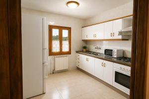 a small kitchen with white cabinets and a window at Winahost Espunyola Berga in L'Espunyola