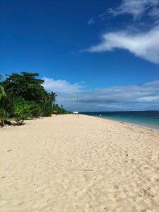 a sandy beach with trees and the ocean at Tugbongan North Siargao in Burgos