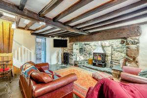 a living room with a stone fireplace and leather furniture at Y Cwtch - Panoramic mountain views within Snowdonia's National Park - 4x4 only in Dolgellau