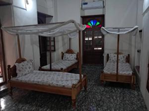 a room with three beds and a stained glass window at MAKAPUS Stone Town Apartments in Zanzibar City