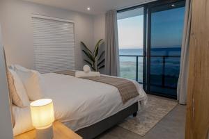 a bedroom with a bed and a view of the ocean at Taluga Beach Villa in St. Helena Bay