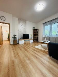 an empty living room with wooden floors and a television at Serenity Apartment in Mariánské Lázně