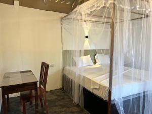 a bedroom with a canopy bed and a table and a chair at Uluwatu Surf Hostel - Arugambay in Arugam Bay