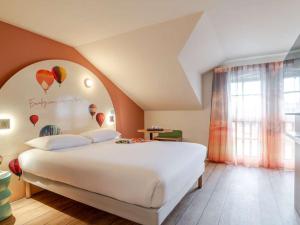 a bedroom with a large white bed with balloons on the wall at ibis Styles Saint-Jean-de-Luz Donibane in Saint-Jean-de-Luz +104 photos