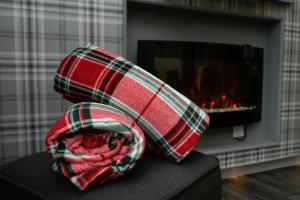 a red and white scarf sitting on a couch in front of a fireplace at Muck in Oban