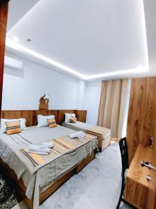 a bedroom with two beds and a table and a desk at Hôtel Dar Farhat in Tunis