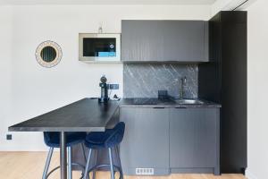 a kitchen with a counter and two blue bar stools at Le Cocon de Brocéliande - Studio cosy et indépendant in Saint-Thurial