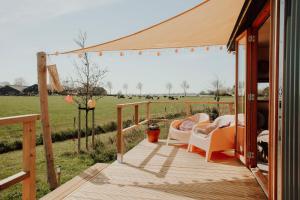 a wooden porch with chairs and a view of a field at Tiny Cabana in Scharendijke