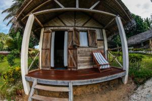 a small house with a thatched roof and a chair at Antafondro Lodge in Sainte Marie