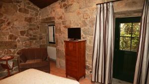 ein Schlafzimmer mit einem Fernseher auf einer Kommode und einem Fenster in der Unterkunft Casa do Sear - Turismo Rural & Spa Exterior in Sanxenxo