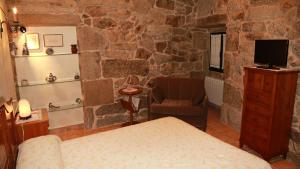 ein Schlafzimmer mit einer Steinwand mit einem Bett und einem Stuhl in der Unterkunft Casa do Sear - Turismo Rural & Spa Exterior in Sanxenxo