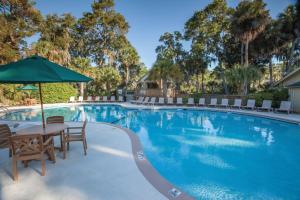 a pool with a table and chairs and an umbrella at Ocean Ridge Resort 2BR Apartment in Edisto Island