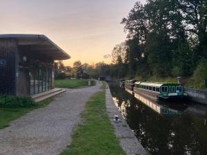 a train parked at a train station next to a canal at Hillcroft Holiday - Dragonfly Lodge, Woody Hut & Alpaca My Tipi Glamping in Billingshurst