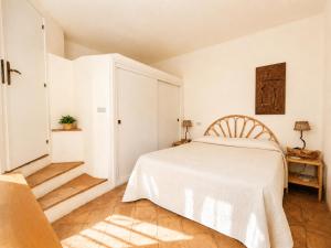 a white bedroom with a bed and a chair at Casa al mare Porto Sole in Baja Sardinia