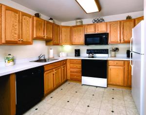a kitchen with wooden cabinets and black and white appliances at Smugglers' Notch Resort 2BR Apartment in Cambridge