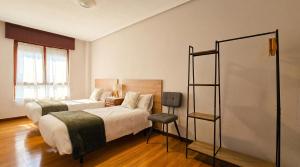 a bedroom with two beds and a chair in it at Las Vistas in Suances +3 photos
