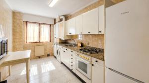 a kitchen with white cabinets and a refrigerator at Las Vistas in Suances