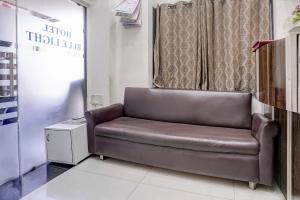 a brown leather chair in a room with a window at FabHotel Blue Light in Mumbai