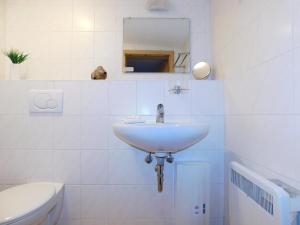 a white bathroom with a sink and a toilet at Sterntaucher Bungalow App 5 in Ahrenshoop