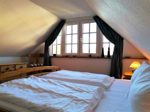 a bedroom with a large white bed with windows at Malvenhus in Ahrenshoop