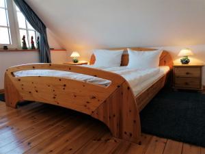 a bedroom with a wooden bed with white sheets and pillows at Malvenhus in Ahrenshoop