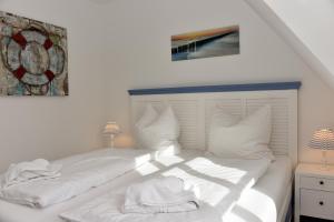 a white bed with white sheets and pillows at Ostseefeeling in Wustrow